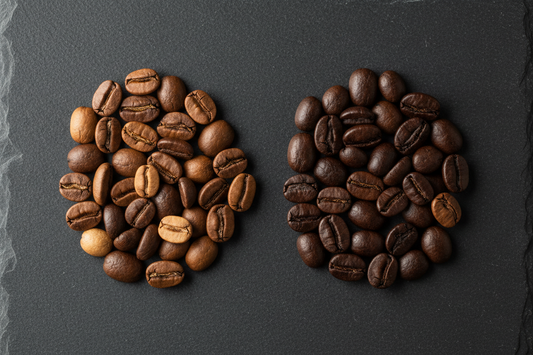 Two groups of coffee beans on a slate surface comparing specialty and commercial roast levels